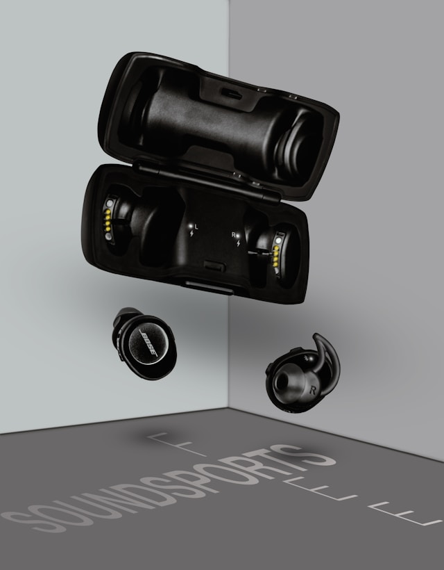 A pair of wireless earbuds beside their charging case on a plain grey surface