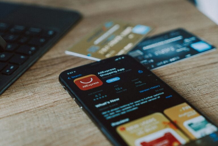 A smartphone on a wooden desk showing the AliExpress shopping app