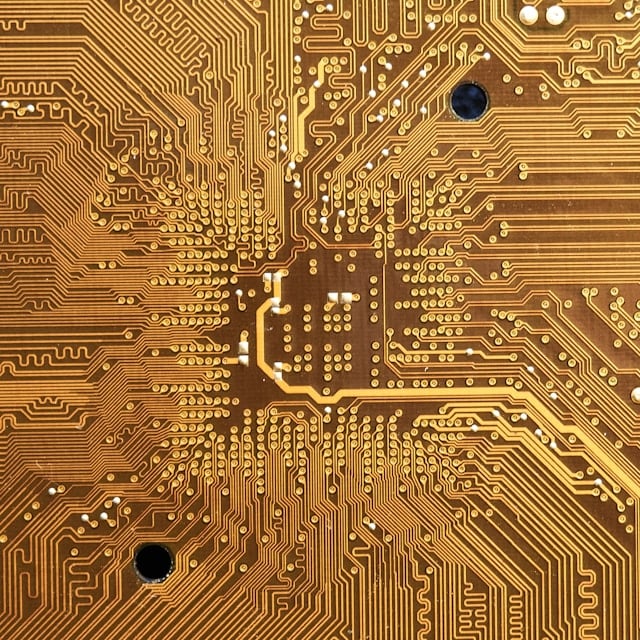 A close-up of a gold-coloured circuit board showing its etched tracks