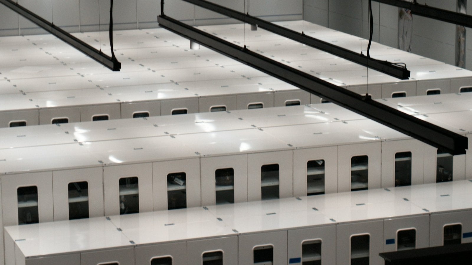 Rows of white server cabinets running the length of a brightly lit data centre