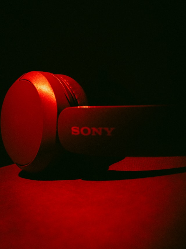 A pair of Sony over-ear headphones lit in deep red against a dark background