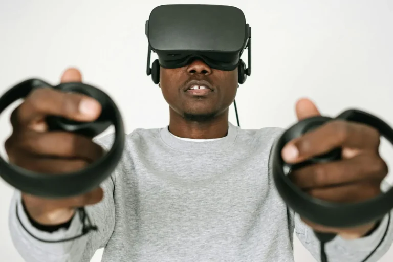 A man wearing a virtual reality headset holding a controller in each outstretched hand
