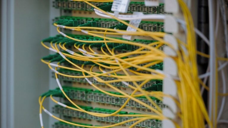Green and yellow fibre optic cables neatly routed across the front of a network rack