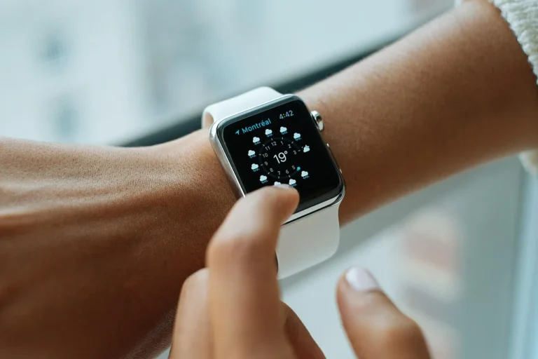 A finger touching the screen of a smartwatch worn on a wrist
