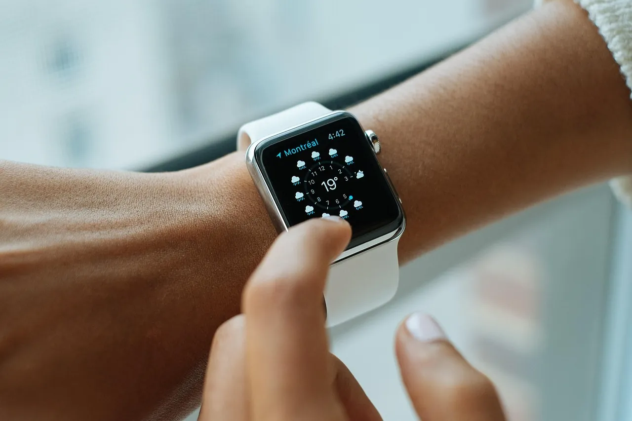 A finger touching the screen of a smartwatch worn on a wrist