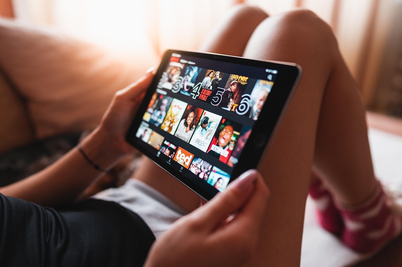 A person holding a tablet showing a grid of streaming thumbnails