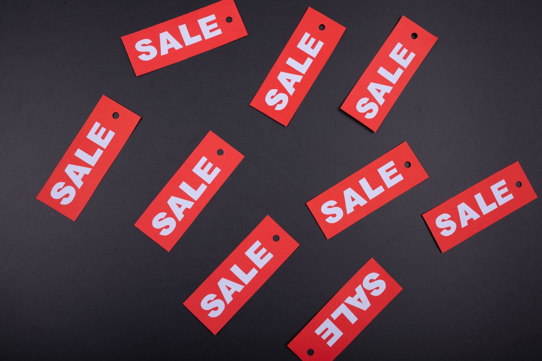 Red cardboard sale tags scattered across a dark grey surface