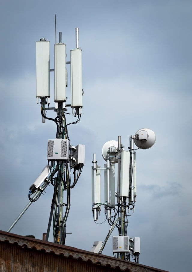 A mobile phone mast carrying several antennas and dishes against a blue sky